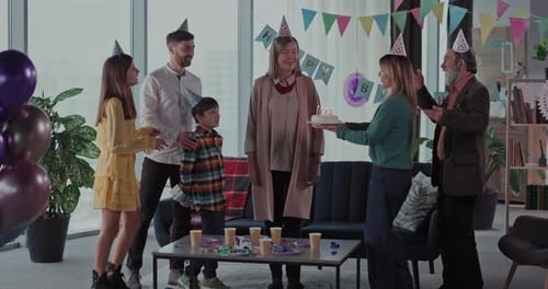 Family celebrating birthday with cake and gifts indoors