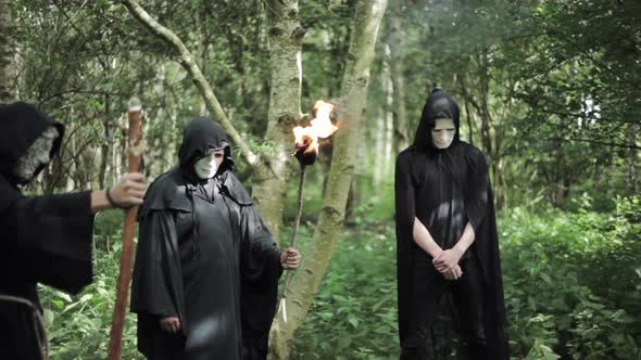 A group of pagan cult members gather in a ritualistic circle in the ...