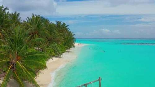 Aerial View on Bikini Beach with Tourists Swim in Turquoise Waters on Maldives Island Thoddoo