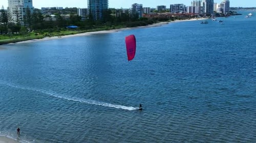 Practica windsurf disfrutando de la soledad en las gloriosas vías fluviales de Gold Coast, detrás hay apartamentos de lujo