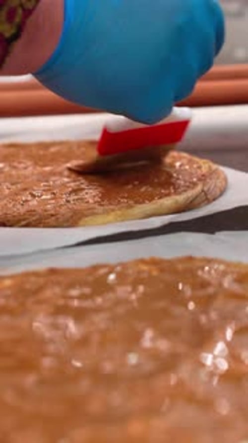 Étaler la sauce au chocolat fondu sur une pâte fine à l'aide d'un pinceau à pâtisserie