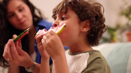 Woman and Child Eat Watermelon Together Indoors