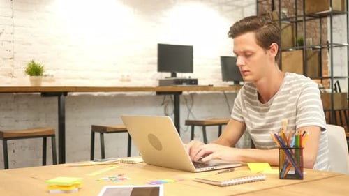 Young Man Leaving Office After Closing Laptop