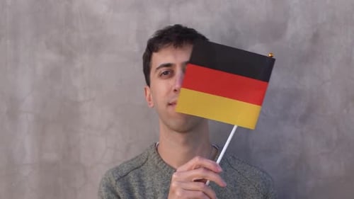 Männlicher Erwachsener, der die deutsche Landesflagge schwenkt. Zeitlupe. Nahaufnahme.