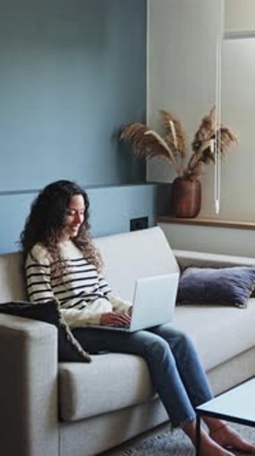 Woman Using Laptop on Couch at Home