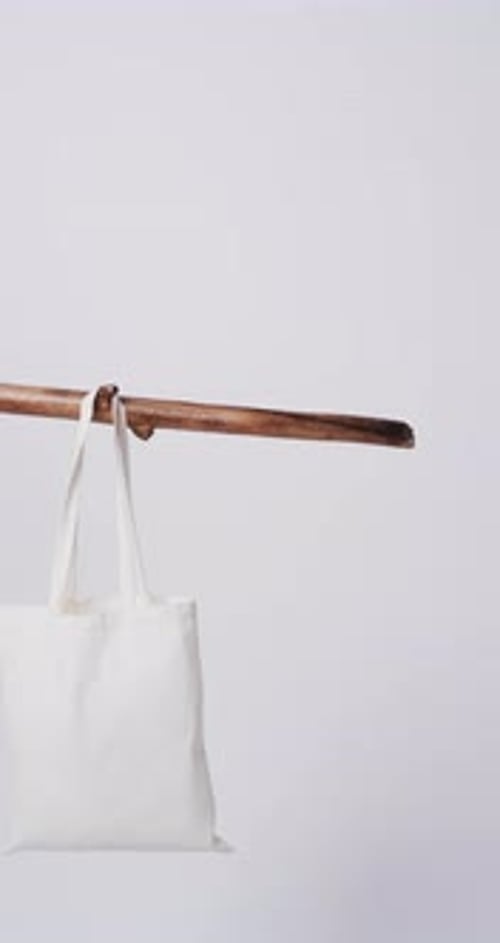 Vídeo vertical de una bolsa de lona blanca colgada de una rama con espacio para copiar sobre fondo blanco