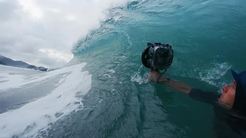 Photographe de surf. Un homme avec une caméra d'action prend une photo de la vague déferlante