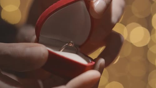 Vor goldenem Hintergrund funkelt der Verlobungsring luxuriös, sein Diamant reflektiert Strahlen, Licht und