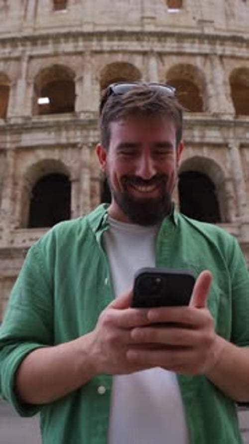 Smiling Man with Smartphone in Front of Colosseum