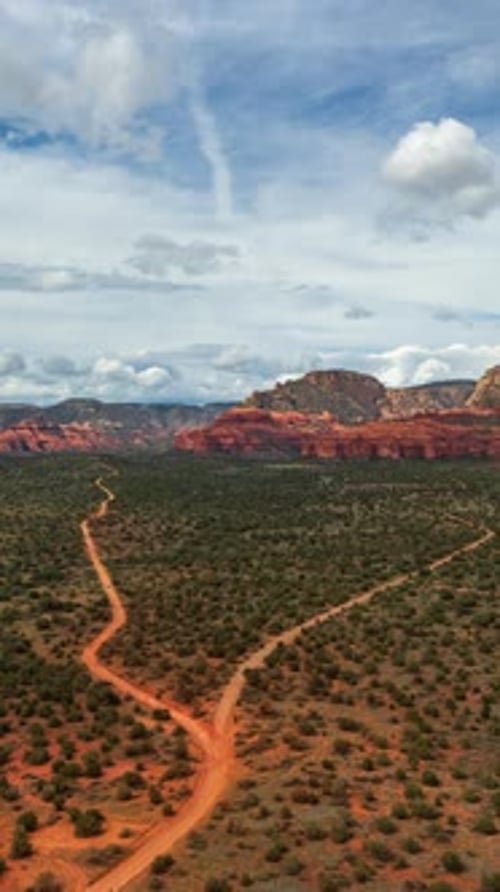 A Winding Dirt Road in Sedona, Arizona Cuts through a Wide Desert Plain, Leading Toward Glowing Red