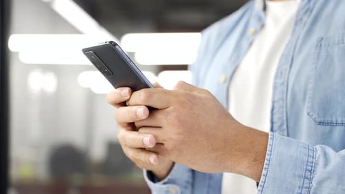 Close up of male hands holding mobile phone in business office. African american businessman