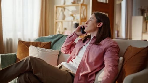 Young Man Relaxing on Sofa Talking on Phone