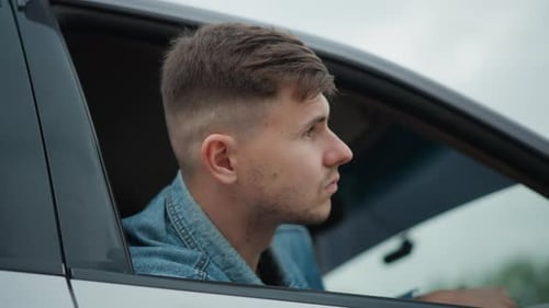 Man in Car Looks Around from Open Window