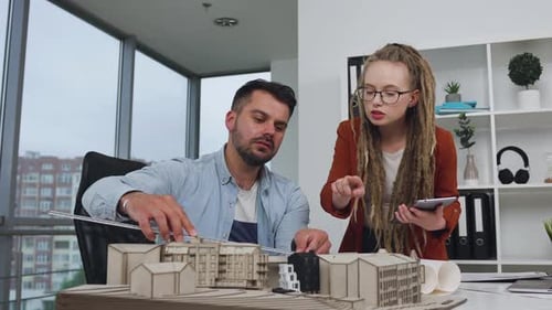 Man architect measuring with ruler the proportions of building model and stylish concentrated woman