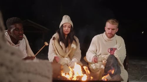 Adult People Roasting Marshmallows Sitting Around Campfire in Winter Night Hike in Forest