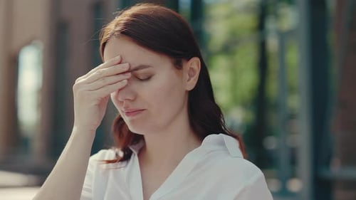 Woman Taking off Glasses Suffering from Headache