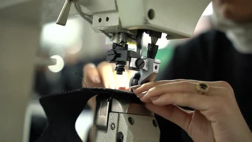 Young Female Worker Sewing in Factory