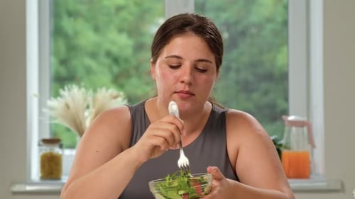 Woman Eats Fresh Salad in Bright Kitchen Setting