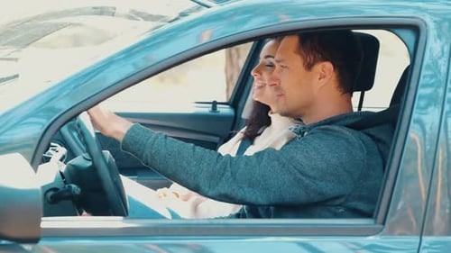 Young Man and Woman Riding Together in Car in Forest