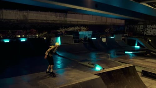 Young skateboarder practicing extreme freestyle trick at urban skatepark ramp at night