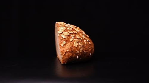 Bread with oatmeal rotates against a black background