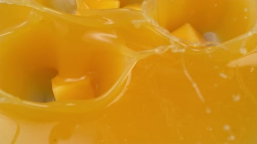 Mango cubes splashing into fresh mango juice