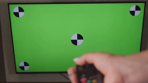 Hand Holding TV Remote Controller Over Green Screen a Modern Television Set