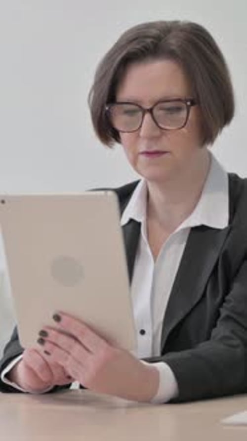 Woman in Business Suit Using Tablet Device at Desk
