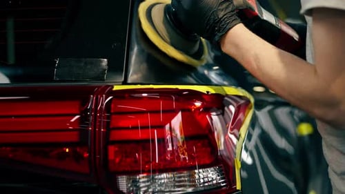 Close Up Car Detailing at a Service Station Black Car is Covered with Yellow Tape the Process of