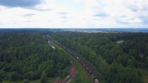 Blick von oben auf den Güterzug vor dem Hintergrund der Stadt und des grünen Waldes