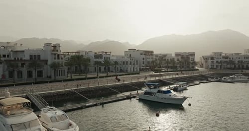 Niedrigwinkel-Luftaufnahme von Sifah Marina, Gebäuden und Bergen, Oman