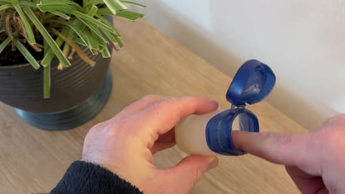Man putting on applying vaseline to lips to lock in moisture, helping skin heal from dryness
