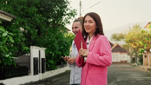 Women Walking on Suburban Street Looking at Houses