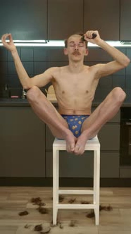 Man Sits on Stool Cutting Hair in Kitchen