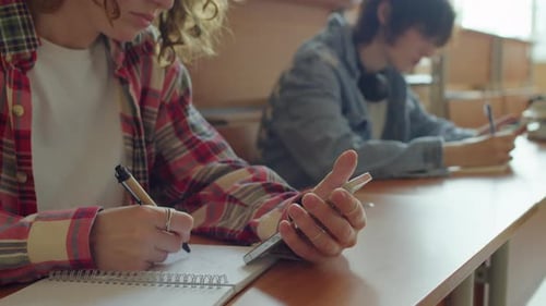 Students Using Phones and Writing in Classroom