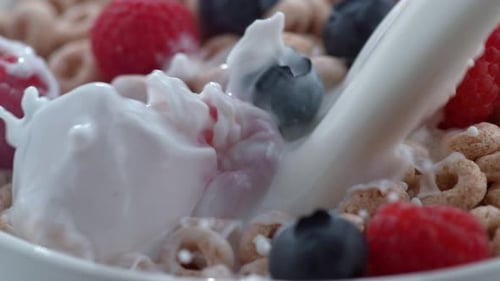 Milk pouring into cereal with berries close-up