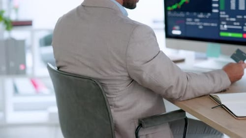 A professional investment banker buying and selling stock on his computer in a modern office