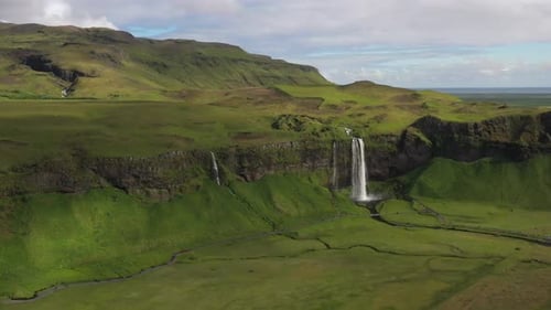 Close Up View of Powerful Waterfall in Stunningly Green and Rugged Icelandic Landscape