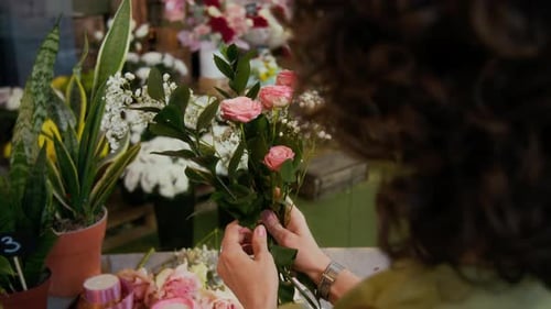 Fleuriste tenant des roses et des gypsophiles arrangeant un nouveau bouquet pendant la journée de travail