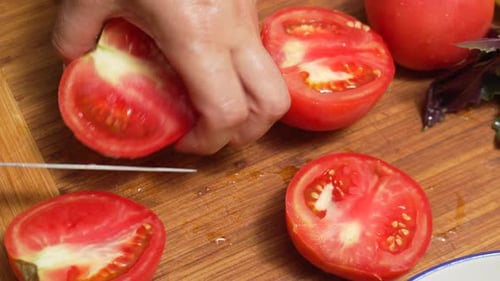 Tomato Being Sliced on a Wooden Cutting Board