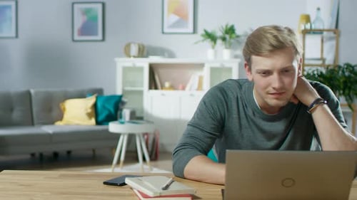 Smiling Young Man Working on Laptop at Home
