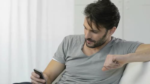 Attractive Man Relaxing on Couch Using Mobile Phone