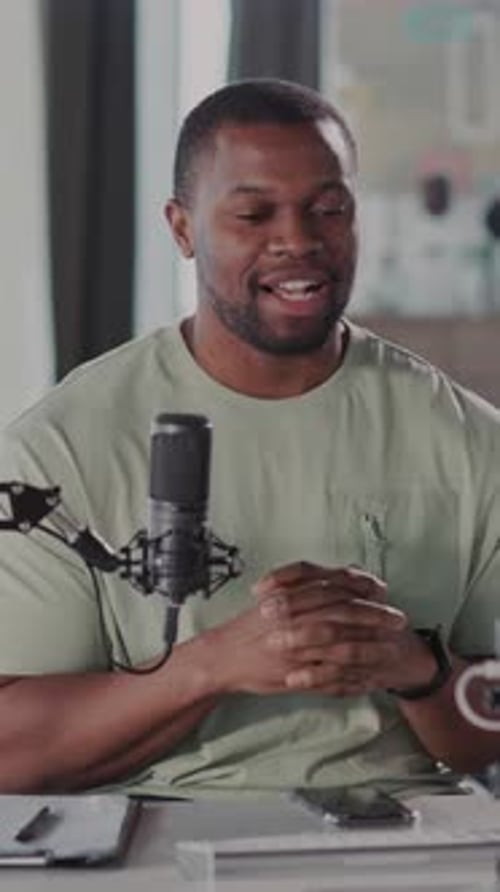 Young adult speaking into a microphone at desk