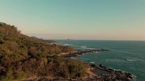Aerial parallax flight revealing rough turquoise waves on Costa Rica coastline
