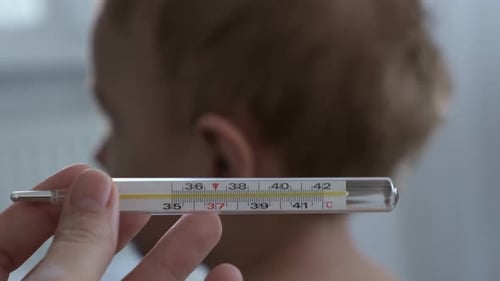 A Mercury or Alcohol Thermometer Against the Background of a Small Child a Concept of Illness Flu or