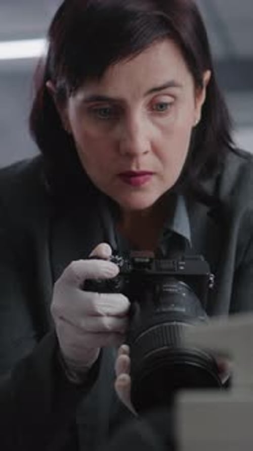 Woman Carefully Photographing Object with Camera and Gloves