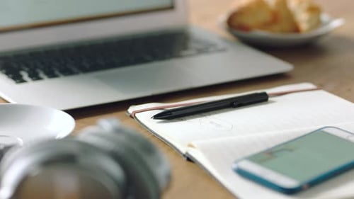 Woman Writes in Notebook While Using Laptop