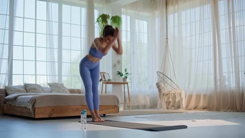 Young Woman Practicing Yoga on Mat in Bright Room