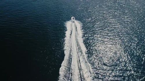 Drone Shot of a Motorboat Cruising at Speed Over the Blue Sparkling Ocean