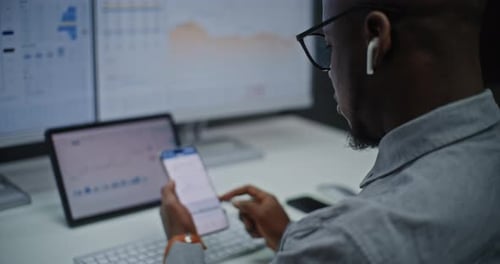 Man Working With Data on Phone in Office